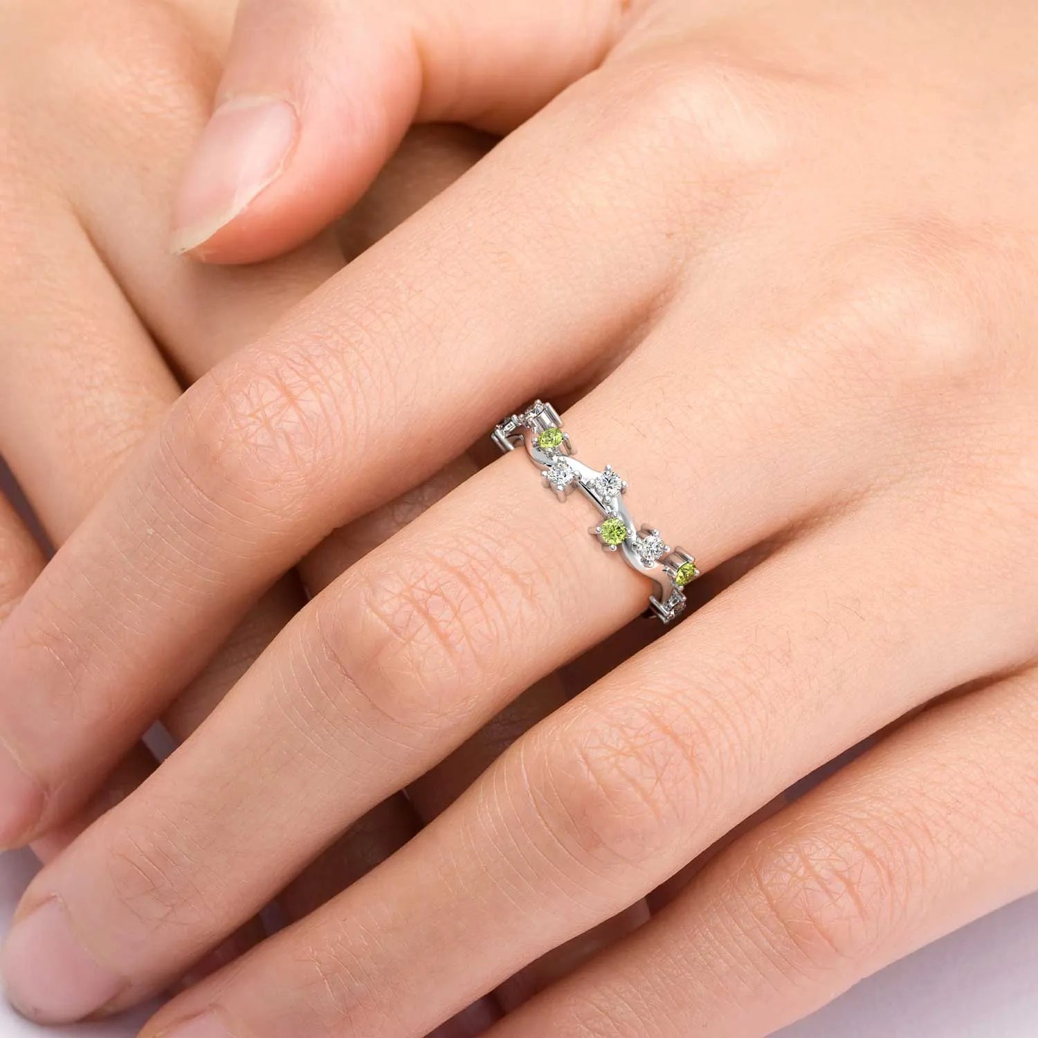 Close-up of a peridot ring worn on hand, featuring a celestial design with white zirconia stones.