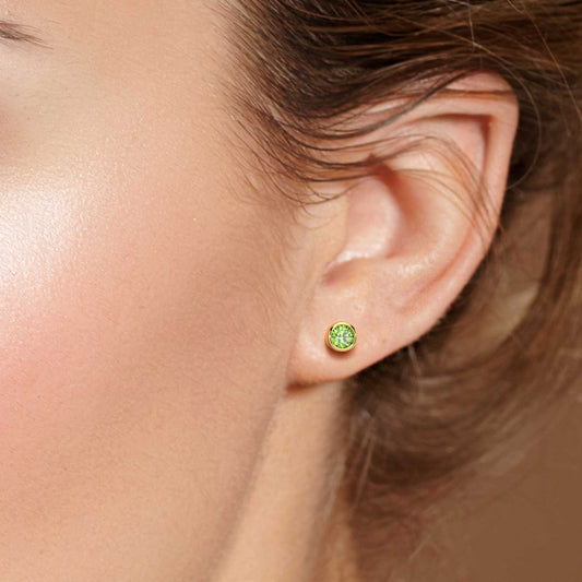 Close-up of peridot earrings with round cut design and gold finish on model